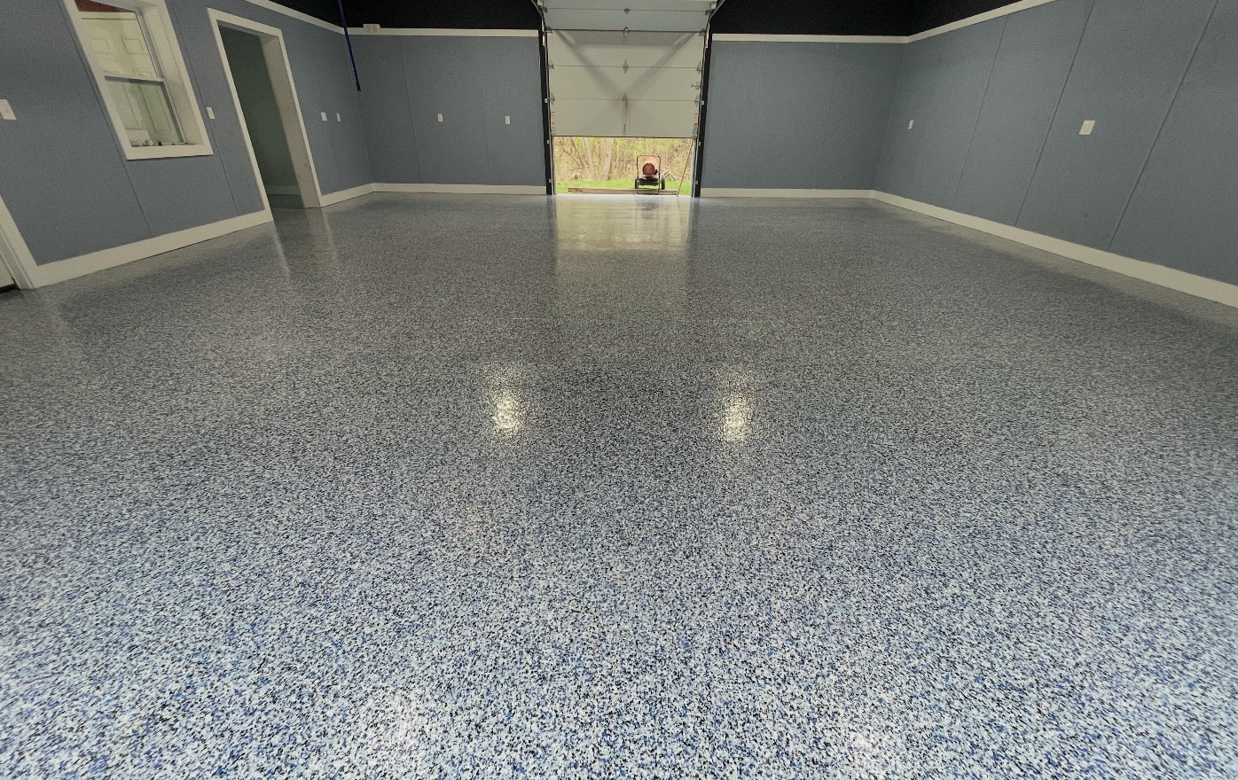 Blue and gray flake epoxy garage floor coating with garage door open to daylight, by HKH Custom Coatings